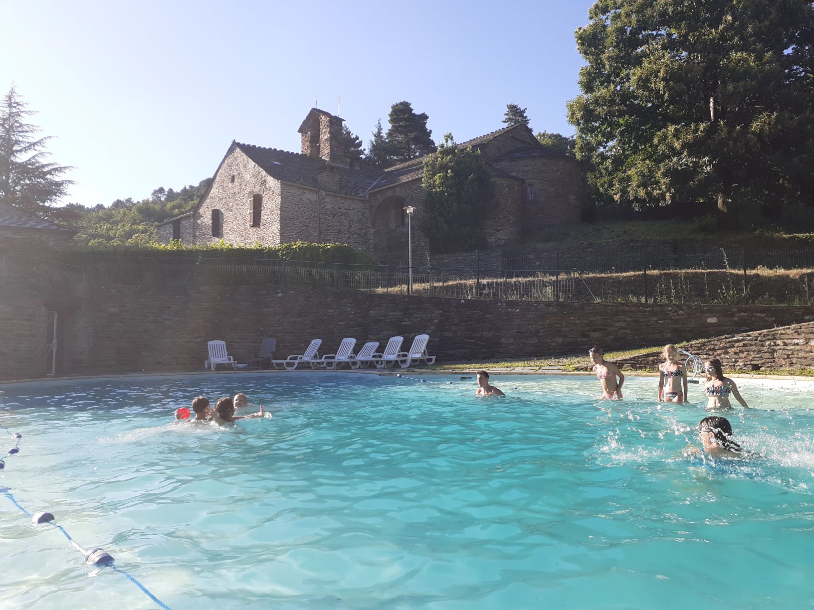 piscine extérieure surplombée par une église romane du XII